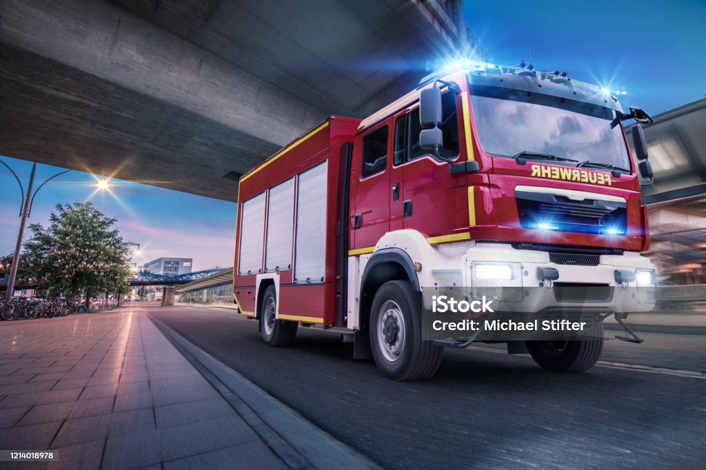 A fire engine in action in the city A fire engine of the fire brigade drives with blue light and Martinshorn through the city to an operation. Fire Engine Stock Photo