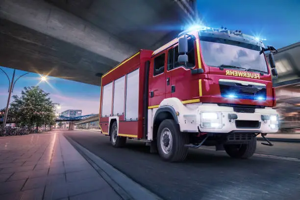 A fire engine of the fire brigade drives with blue light and Martinshorn through the city to an operation.