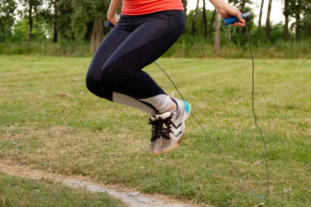 Low section of a woman skipping rope outdoors.