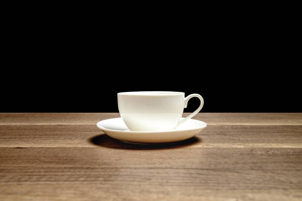 istock White glossy ceramic cup on saucer placed on wooden table with black background 1214020235
