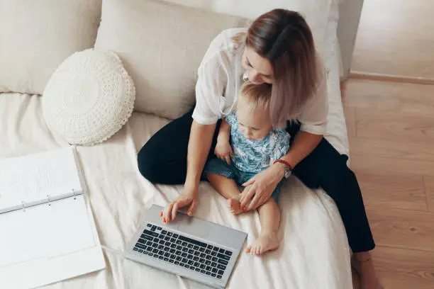 Photo of Modern woman working with child. Multi-tasking, freelance and motherhood concept