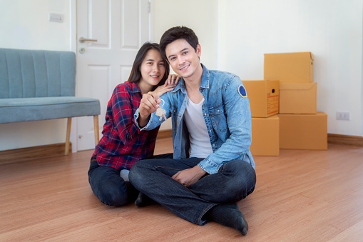 Happy smiling asian young couple showing a keys of their new house