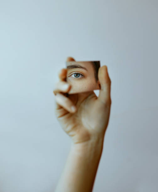 mano recortada sosteniendo el espejo con reflejo de ojo - reflejados en el espejo fotografías e imágenes de stock