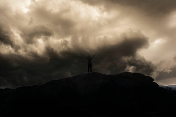 istock Silhouette of free man under dark clouds. 1214032246