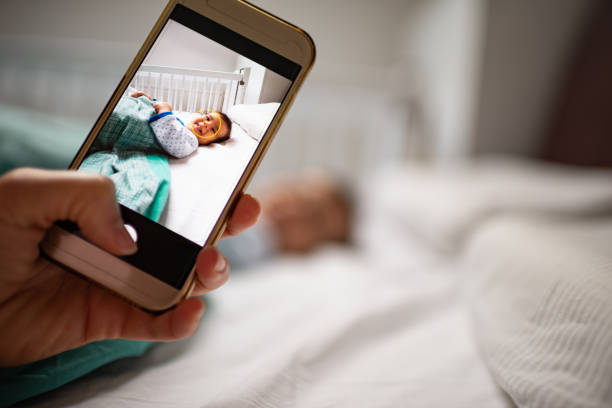 Parent taking photo of a baby with smartphone. Digital family memories.