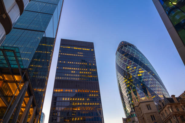 Low angle view of illuminated skyscrapers in the city of London Low angle view of illuminated skyscrapers in the city of London at evening gherkin london night stock pictures, royalty-free photos & images