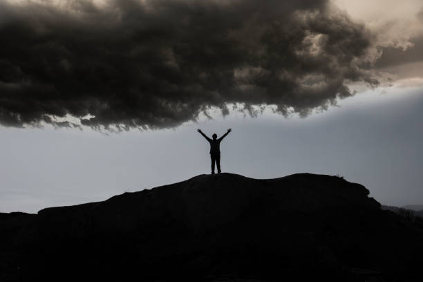 istock Silhouette of free man under dark clouds. 1214033216