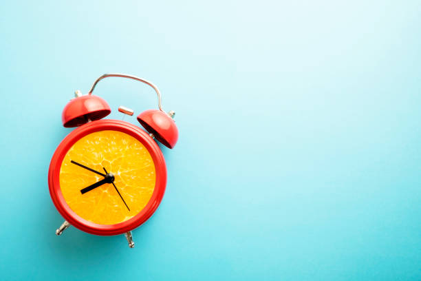 istock Red alarm clock with a fresh orange dial. Retro styre 'orange' clock with bells on blue background. 1214034897