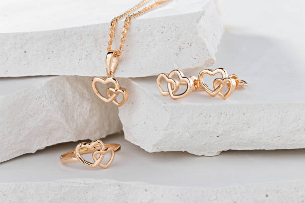 conjunto de joyas de corazones en forma de anillo de oro rosa, collar colgante y pendientes de perno sobre fondo blanco - heart pendant fotografías e imágenes de stock