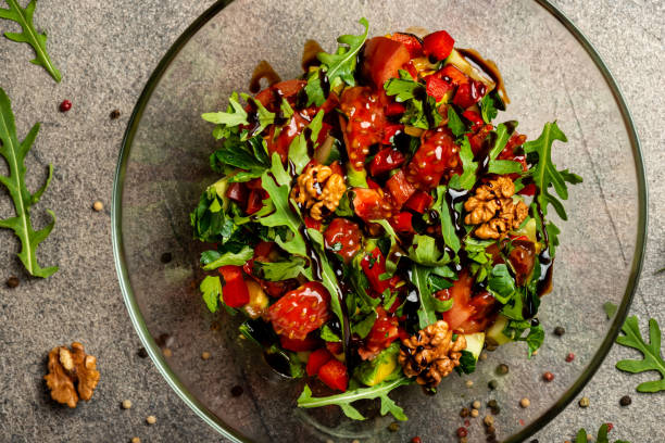 istock Vegetable salad with arugula, tomatoes, avocado, splashed with balsamic sauce in a glass bowl. Top view. 1214035408