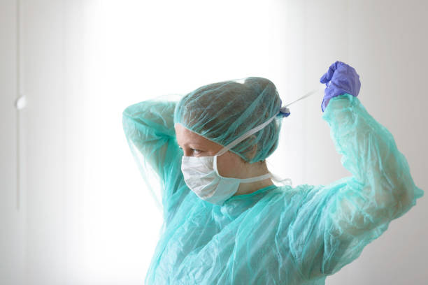 Female doctor tying protective face mask to prevent from virus disease Nurse wearing protective mask and gloves. New coronavirus Covid-19 from China. Female surgeon wearing her surgical mask protective sportswear stock pictures, royalty-free photos & images