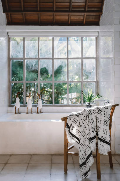 istock Modern bathroom interior, chair near built bathtub against large window 1214041052