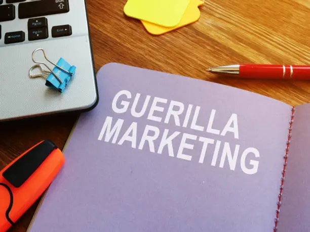 Photo of Guerilla marketing guide and laptop on the desk.