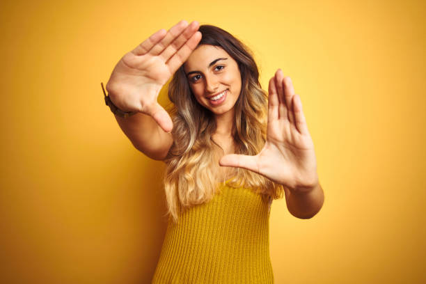 istock Young beautiful woman wearing t-shirt over yellow isolated background doing frame using hands palms and fingers, camera perspective 1214042495