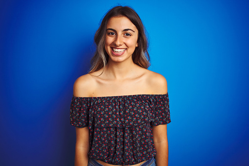 Young beautiful woman wearing floral t-shirt over blue isolated background with a happy and cool smile on face. Lucky person.