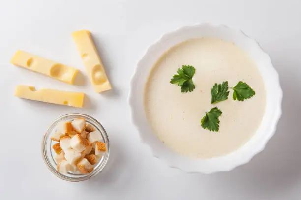 Cheese cream soup with sliced ??cheese and bread crumbs on a white background