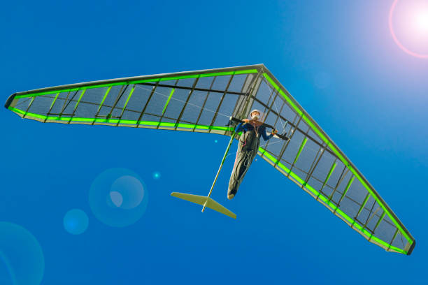 Bright hang glider wing in the blue sky with sun flare. Dream to fly like a bird Bright hang glider wing in the blue sky with sun flare. Dream to fly like a bird glider hang glider hanging sky stock pictures, royalty-free photos & images