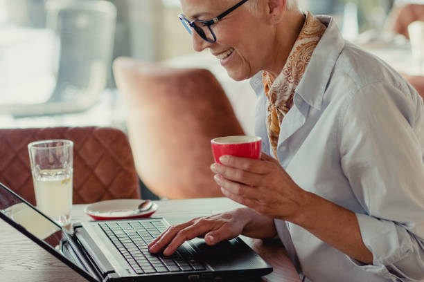 istock Senior woman using laptop in a coffee shop 1214047752