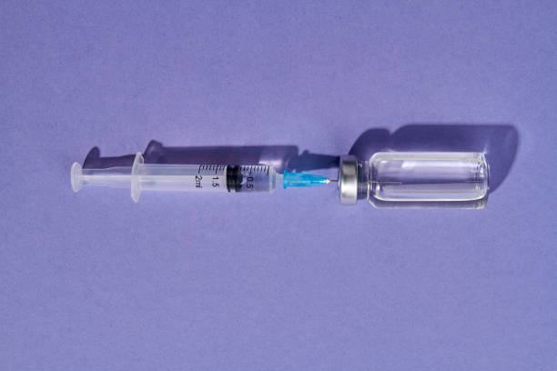 istock Close up syringe needle injected into medical vial bottle. 1214048025