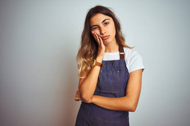 young beautiful woman wearing apron over grey isolated background thinking looking tired and bored with depression problems with crossed arms. - stereotypical housewife depression sadness women imagens e fotografias de stock