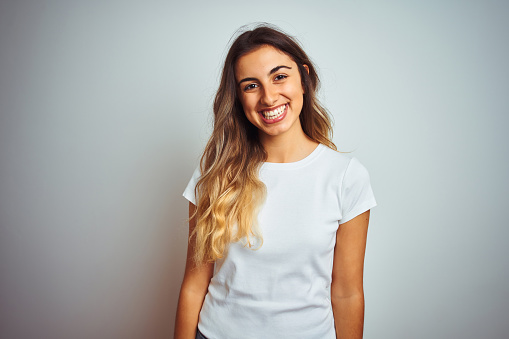 Young beautiful woman wearing casual white t-shirt over isolated background with a happy and cool smile on face. Lucky person.