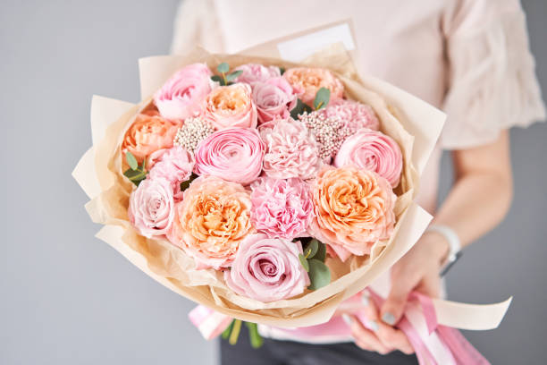 tienda de flores europea. hermoso ramo de flores mezcladas en manos de las mujeres. el trabajo de la floristería en una floristería. entrega flor fresca cortada. - multi colored flower red flower head fotografías e imágenes de stock