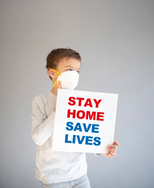 istock boy with protective mask holding sign during corona crisis 1214053002