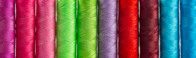Panoramic detail view of differently colored spools of thread