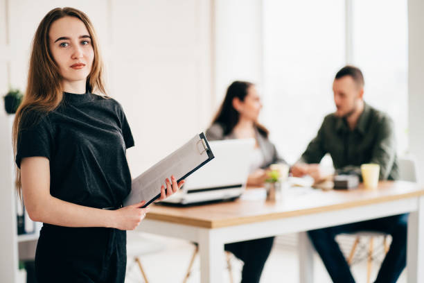 istock woman standing with her co-workers at background 1214056590