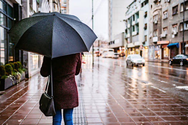 istock Woman walking downtown in rain 1214056789