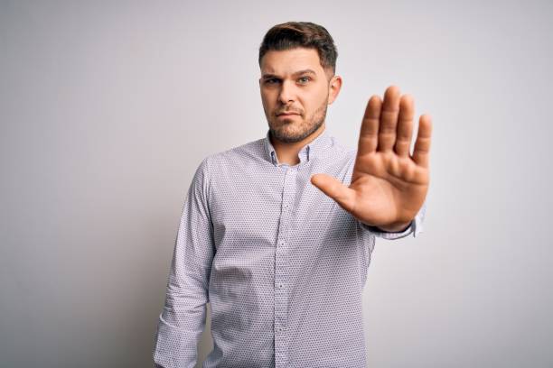 istock Young business man with blue eyes standing over isolated background doing stop sing with palm of the hand. Warning expression with negative and serious gesture on the face. 1214057196