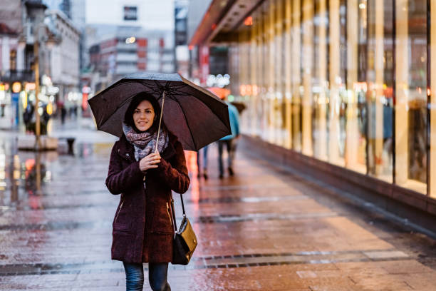 istock Woman walking downtown in rain 1214057332
