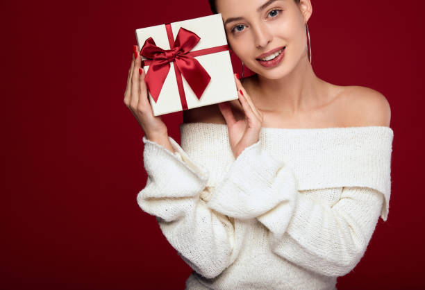 A pretty Caucasian woman with a tiny gift looks straight. stock photo