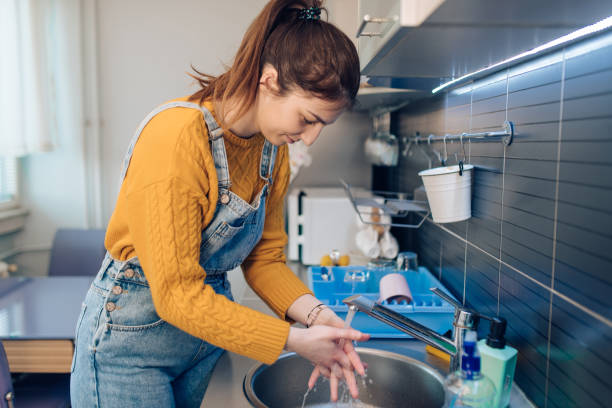 istock Young woman washing hands at home 1214057673