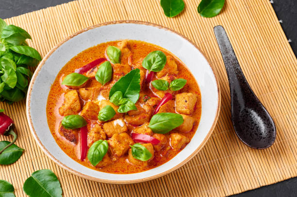 istock Thai Panang Chicken Curry in white plate at black slate background. Phanaeng Curry is thai cuisine dish with chicken, kaffir lime leaves, red curry sauce and vegetables. Thai food. Thailand meal 1214058996