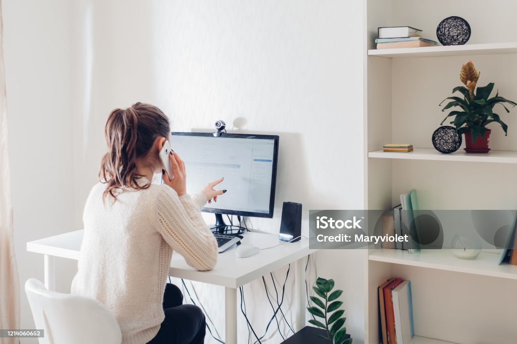 Work from home during coromavirus pandemic. Woman stays home. Workspace of freelancer. Office interior with computer Work from home during coromavirus pandemic. Woman stays home talking on phone. Workspace of freelancer. Office interior with computer Working At Home Stock Photo
