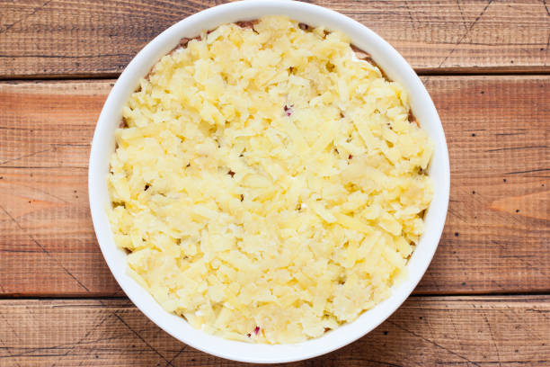 istock Step-by-step preparation of a traditional Russian spring Mimosa salad, step 4 - adding grated boiled potatoes to the salad, top view, selective focus 1214063352