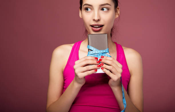 istock A thin young girl bites a bar of chocolate. 1214063630