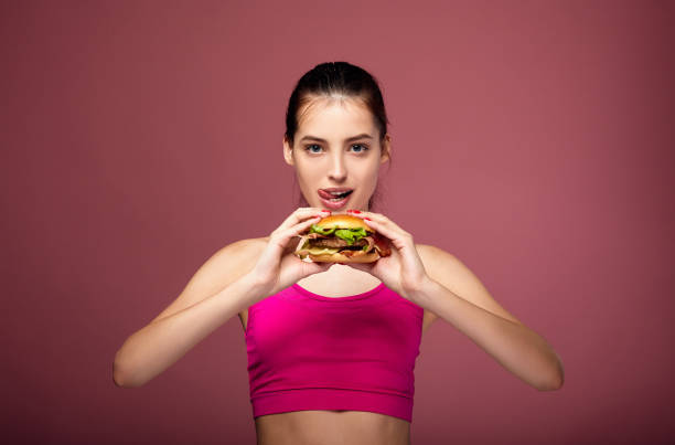 istock Athletic white girl with a beautiful body eats a burger. 1214063760