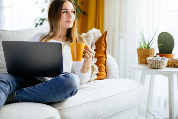 istock Happy smiling woman sitting on sofa and using laptop 1214063798