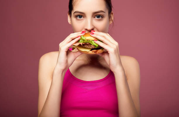 istock Good-looking woman eating cheeseburger. 1214064571