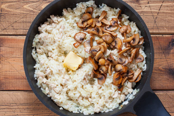 istock Step-by-step preparation of risotto with mushrooms and chicken breast, step 6 - adding fried mushrooms, butter, top view, selective focus 1214064764