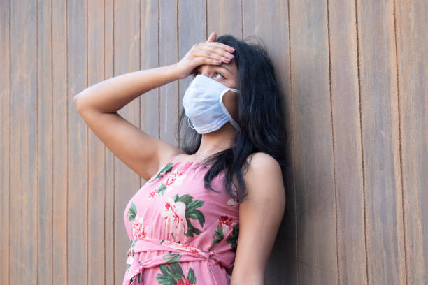 Worried woman touching her forehead to assess high temperature due to infectious COVID-19 disease Worried coronavirus infected woman wearing protective mask and checking her temperature by touching her forehead with palm of hand immune system stock pictures, royalty-free photos & images