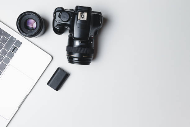 istock Photographer's workplace on a white background. Modern laptop, digital camera, lens, battery, smartphone. Minimalism. Top view. Copy space. Equipment for the photographer. The concept of freelancing 1214067179