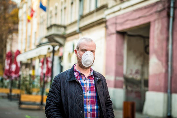 istock Man wearing protective face mask outdoors on city street 1214067682