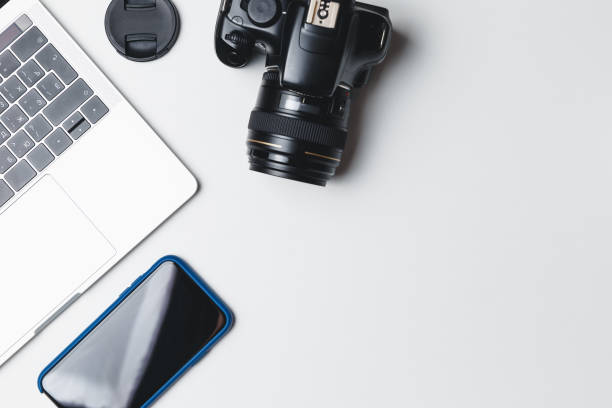 istock Photographer's workplace on a white background. Modern laptop, digital camera, lens, battery, smartphone. Minimalism. Top view. Copy space. Equipment for the photographer. The concept of freelancing 1214068457