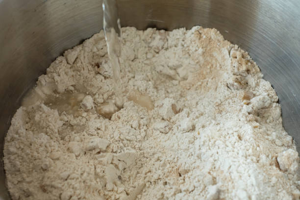 istock Water pouring in flour and yeast close-up 1214069110