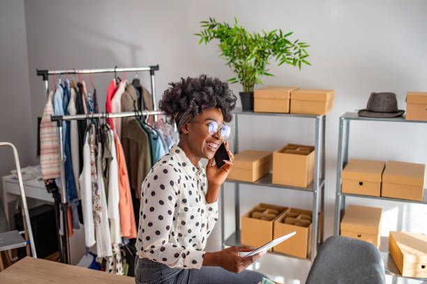 istock Young woman talking on a cellphone while working on her tablet PC at home 1214070182