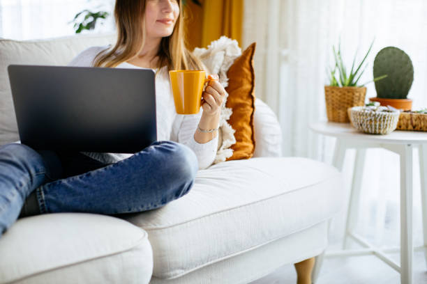 istock Happy smiling woman sitting on sofa and using laptop 1214072258