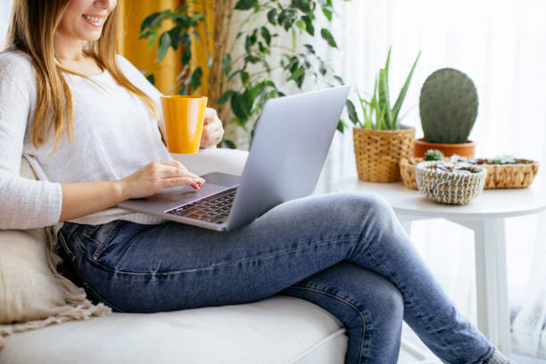 istock Happy smiling woman sitting on sofa and using laptop 1214075998